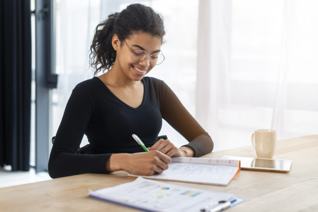 Moça jovem estudando e escrevendo no caderno